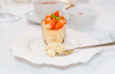 Fresh strawberry cheesecake on a ceramic plate on a white festive table
