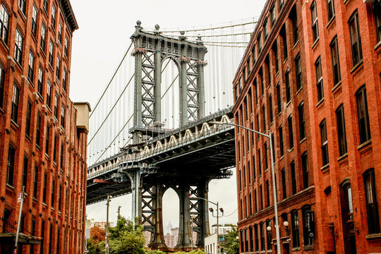 Manhattan bridge seen from Washington St alley enclosed by two brick buildings on a cloudy and rainy day, Brooklyn Dumbo, New York, USA.