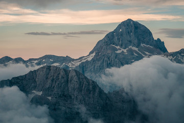 Sunset view on Triglav summit in clouds, in Julian Alps, Slovenia after hike on Jubilee via ferrata, hut Koča na Kredarici visible