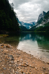Beatiful view over the Gosau see in Austria towards Dachstein mountain, during fall with cloudy weather over the mountains, sand beach in the foreground