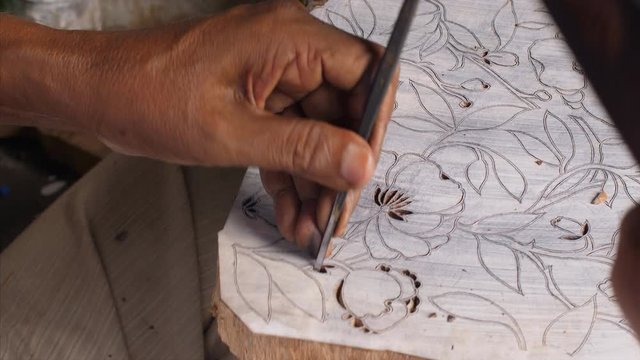 Man carving a beautiful floral design for a wooden block printing  . 