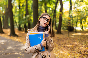 Young woman walking down the park and talking on her mobile phone