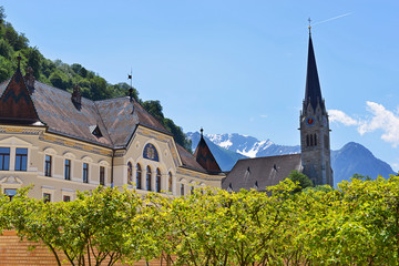 The spire of Vaduz Cathedral on the background of snowy alpine peaks