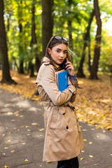 Young woman walking down the park and talking on her mobile phone