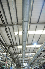 Industrial metal air flow and air conditioning pipes on the ceiling of an industrial factory. keeping the air fresh and clean for health and safety purposes. Healthy working environment for workers