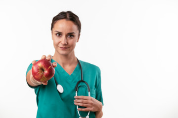 Beautiful female doctor in green uniform. Portrait of nurse holding an apple. 