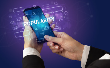 Female hand typing on smartphone with POPULARITY inscription, social media concept