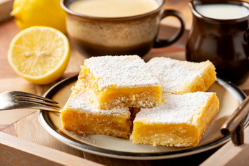 Homemade lemon bars with shortbread crust, on wooden background. 