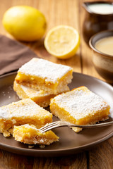 Homemade lemon bars with shortbread crust, on wooden background. 