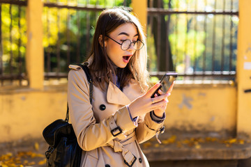 Happy beautiful woman calling by phone via air pods in autumn park