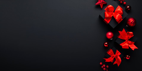 Merry Christmas and Happy Holidays greeting card, frame, banner. New Year. Noel. Black  and red Christmas gifts, ornaments on black background top view. Winter holiday xmas theme. Flat lay.