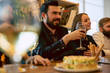 Happy co-workers celebrating while company party, corporate event. Young caucasian people in business attire talking, drinking wine. Concept of office culture, teamwork, friendship, holidays, weekend.