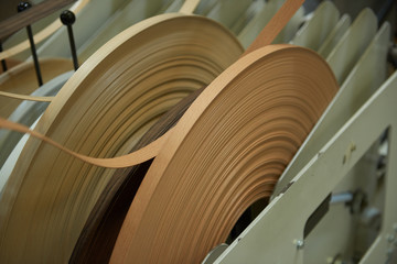 An automatic laminate edge trimming machine in a factory setting. Laminate furniture corner finishings for a finished look and chip board wood protection. Hard wearing flat pack furniture corner edge 