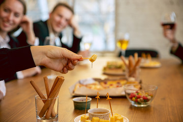 Happy co-workers celebrating while company party, corporate event. Young caucasian people in business attire talk, drink wine, eat snacks. Concept of office culture, teamwork, friendship, weekend.