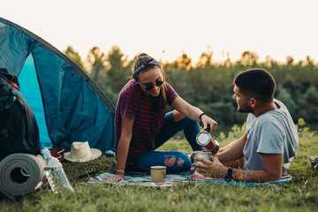 couple drinking coffee, camping by the river outdoor