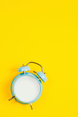 Vintage blue blank alarm clock on a yellow background with marskmallows as a decoratio