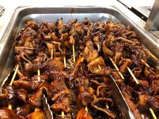 Metal tray of barbeque pig's ears on sticks, a famous street food in the Philippines.