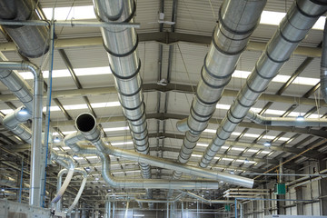 Industrial metal air flow and air conditioning pipes on the ceiling of an industrial factory. keeping the air fresh and clean for health and safety purposes. Healthy working environment for workers