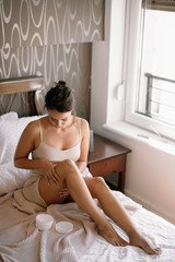 Obraz na płótnie Canvas Woman applying body cream on her leg in bedroom.