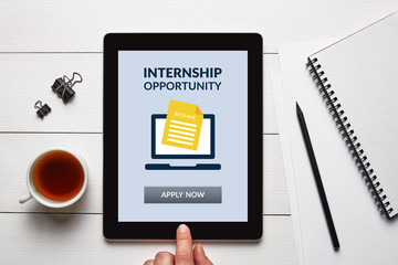 Internship concept on tablet screen over white wooden desk