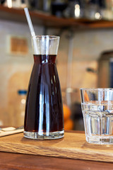 Glass with cold brew coffee and glass with water on a coffee shop counter