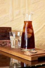 Glass with cold brew coffee and glass with water on table at coffee shop