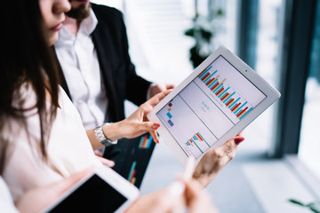 Group of office workers discussing financial statistics on tablet