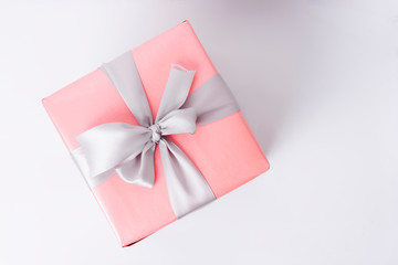 Top view of pink gift box with ribbon on white