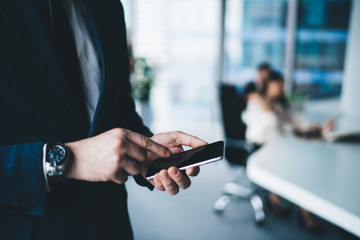 Man in business suit standing and using smartphone