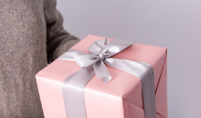 Close up of female hands holding gift box wrapped with ribbon. Gift in the hands of a woman.