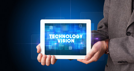 Young business person working on tablet and shows the inscription: TECHNOLOGY VISION