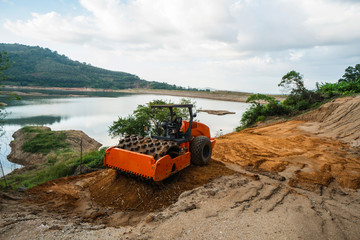 Soil compactor with vibratory padfoot drum. Heavy duty machinery working on highway construction...