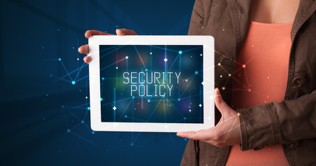 Young business person working on tablet and shows the digital sign: SECURITY POLICY