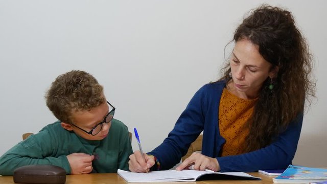 little boy doing his homework with mother