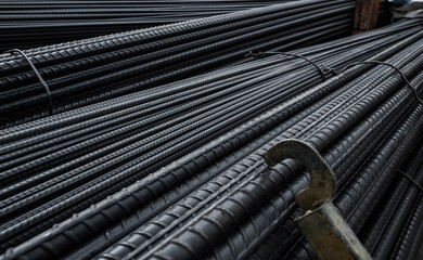 Building armature in the warehouse of metallurgical products or on construction site. Stack of heavy metal reinforcement bars with periodic profile texture. Steel construction armature.