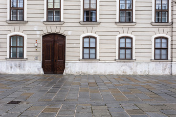 Several windows along with vintage wooden doors on display outside classic european building