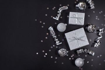 Present boxes, silver christmas balls and ribbons on black background with copy space