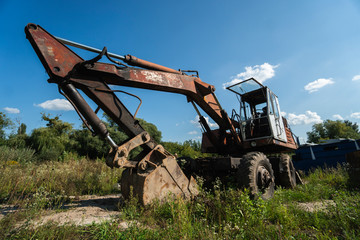 Old excavator in the field in sunny day.