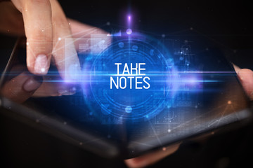 Young man holding a foldable smartphone with TAKE NOTES inscription, educational concept