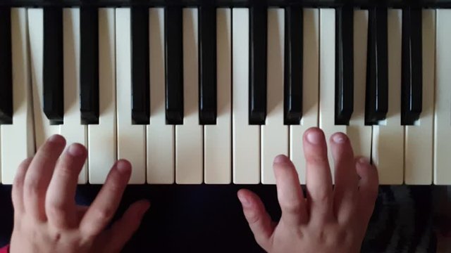 a child plays the piano .hands and keys close up