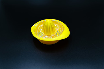 leere, gelbe Zitronenpresse auf schwarzem Hintergrund.