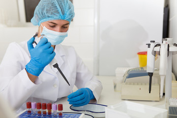 Female in medical gown and gloves making scientific experiments