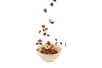 Chocolate corn flakes falling to the white bowl isolated on white. Motion.