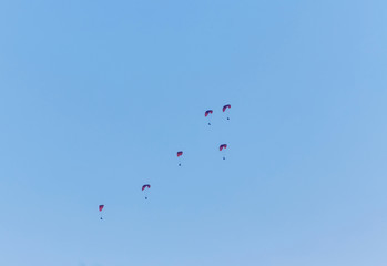Silhouette of powered paraglider soaring flight over the sea against marvellous orange sunset sky.
