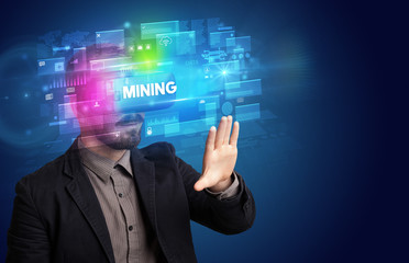 Businessman looking through Virtual Reality glasses with MINING inscription, innovative security concept