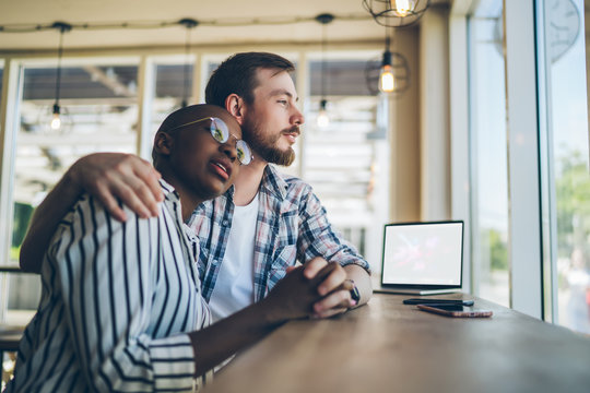 Lovely multiracial couple daydreaming at cafe table together