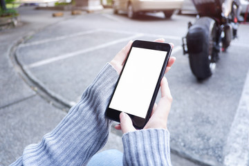 Mockup picture of business woman’s hands holding smart phone with white blank screen in modern place.
