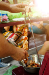 A man removes kebab meat from skewers in a plate. BBQ party.