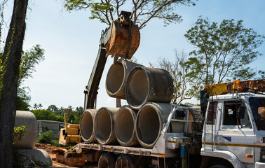 Using an excavator to transfer large pipes to a vehicle.