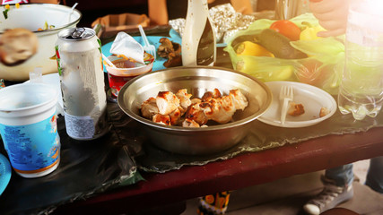 BBQ mess on the table. Barbecue outside, a table filled with plates with various foods, grilled vegetables and meat skewers, beer and wine in cans and glasses